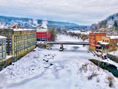 a city covered in snow with a bridge and buildings at The Inn At Stone Mill in Little Falls