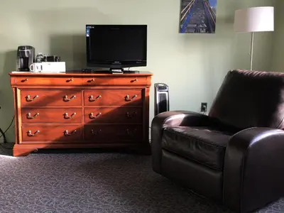 a living room with a chair and a television on a dresser at The Inn At Stone Mill in Little Falls