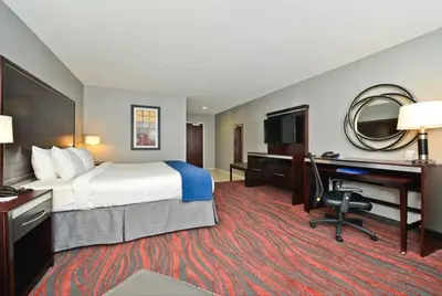 a hotel room with a bed and a desk with a computer at Holiday Inn Express & Suites Utica by IHG in Utica