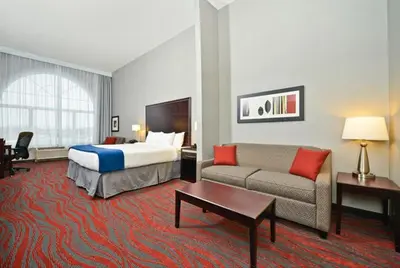 a hotel room with a bed and a couch at Holiday Inn Express & Suites Utica by IHG in Utica