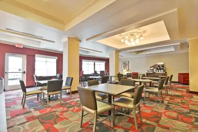 a dining room with tables and chairs on a rug at Holiday Inn Express & Suites Utica by IHG in Utica