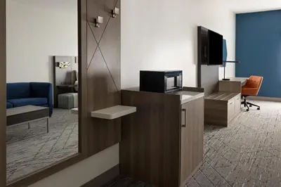a room with a tv and a chair and a mirror at Holiday Inn Express and Suites Meriden by IHG in Meriden