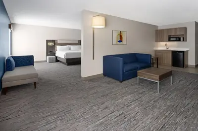 a hotel room with a bed and a blue couch and chair at Holiday Inn Express and Suites Meriden by IHG in Meriden