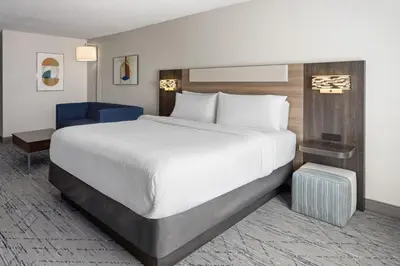 a bedroom with a large bed and a blue chair at Holiday Inn Express and Suites Meriden by IHG in Meriden