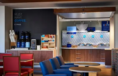 a coffee shop with blue chairs and a table at Holiday Inn Express - Newark Airport - Elizabeth by IHG in Elizabeth