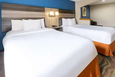 two beds in a hotel room with white sheets at Baymont by Wyndham Budd Lake in Budd Lake