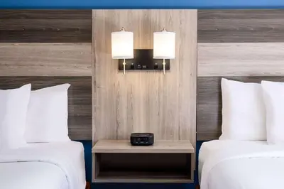 a hotel room with two beds and a clock on a night stand at Baymont by Wyndham Budd Lake in Budd Lake