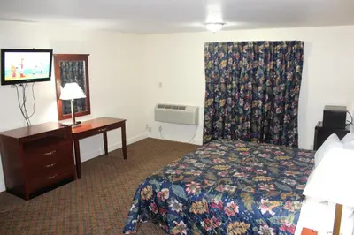 a hotel room with a bed and a desk and a television at Passport Inn and Suites - Middletown in Middletown