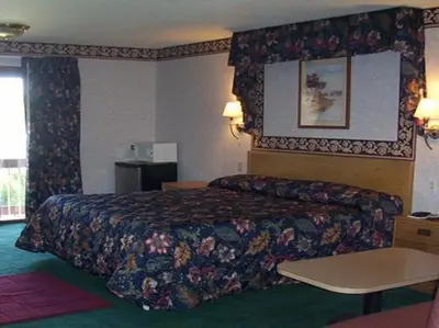a hotel room with a bed with a floral bedspread at Passport Inn and Suites - Middletown in Middletown
