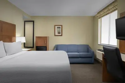 a hotel room with a bed and a blue couch at Holiday Inn Express Manhattan Midtown West by IHG in New York