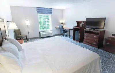 a hotel room with a bed and a flat screen tv at Hampton Inn & Suites Berkshires-Lenox in Lenox