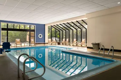a large swimming pool with chairs and windows at DoubleTree by Hilton Bradley International Airport in Windsor Locks