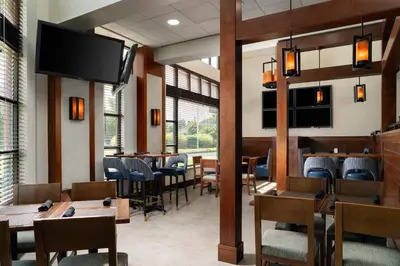 a restaurant with tables and chairs and a flat screen tv at DoubleTree by Hilton Bradley International Airport in Windsor Locks