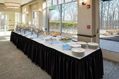 a long table with plates and food on it at Hilton Garden Inn Hartford North-Bradley International Airport in Windsor