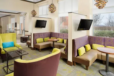 a waiting room with couches and tables and televisions at Hilton Garden Inn Hartford North-Bradley International Airport in Windsor