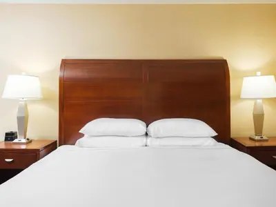 a bedroom with a large bed with white sheets and two lamps at DoubleTree by Hilton Stamford in Stamford