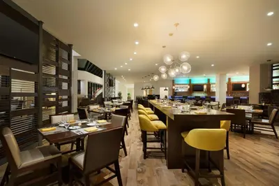 a restaurant with wooden tables and yellow chairs at DoubleTree by Hilton Stamford in Stamford