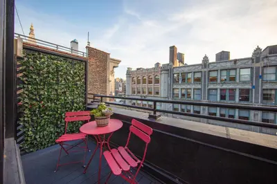 a red table and chairs on a balcony with buildings at Hotel Henri NY in New York
