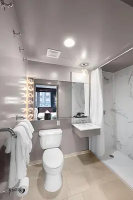 a white bathroom with a toilet and a sink at Hotel Henri NY in New York