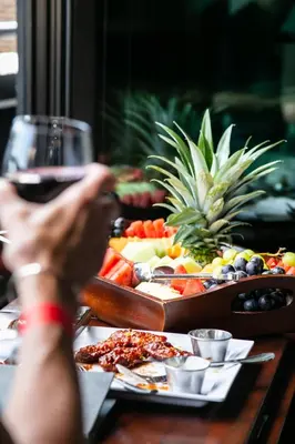 a person holding a glass of wine next to a table of food at Hotel Henri NY in New York