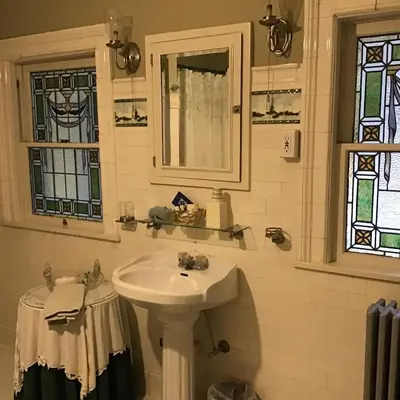 a white sink in a bathroom with stained glass windows at Brookview Manor Inn in Canadensis