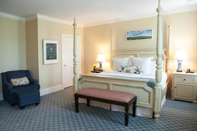 a bedroom with a canopy bed and a chair at Delamar Southport in Southport