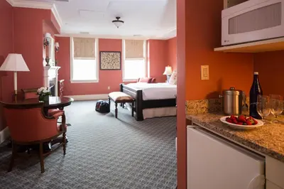 a hotel room with a bedroom with a bed and a kitchen at Delamar Southport in Southport