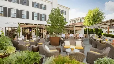 an outdoor patio with wicker chairs and tables at Delamar Southport in Southport