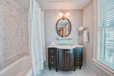 a bathroom with a sink and a mirror and a tub at Delamar Southport in Southport