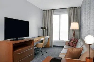 a hotel room with a desk with a television and a couch at Residence Inn by Marriott Norwalk in Norwalk