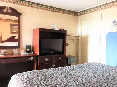 a bedroom with a bed and a dresser with a television at Days Inn by Wyndham Tannersville in Tannersville
