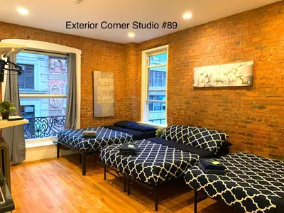 a room with two beds and a brick wall at NYC Empire Apartments in New York