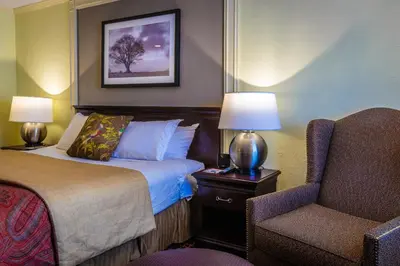 a hotel room with a bed and a chair at The Olde Mill Inn Basking Ridge in Basking Ridge