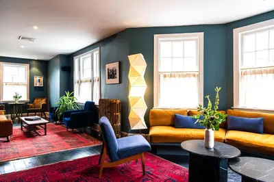 a living room with couches and tables and windows at Hotel Kinsley, a Member of Design Hotels in Kingston