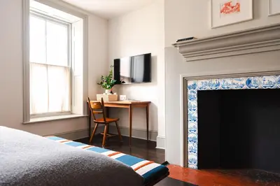 a bedroom with a fireplace with a desk and a television at Hotel Kinsley, a Member of Design Hotels in Kingston