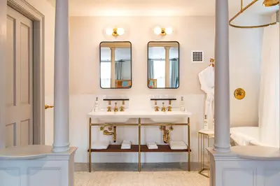 a bathroom with two sinks and two mirrors at Hotel Kinsley, a Member of Design Hotels in Kingston