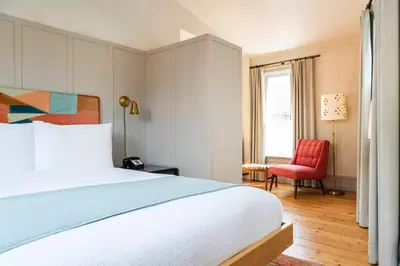 a bedroom with a bed and a red chair at Hotel Kinsley, a Member of Design Hotels in Kingston