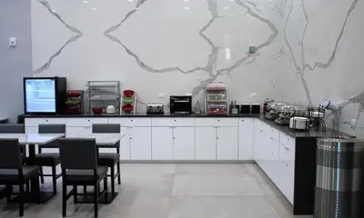 a restaurant with white cabinets and tables and a marble wall at Wingate by Wyndham Long Island City in Queens