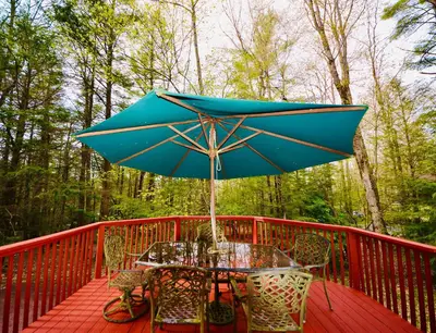 a table with a blue umbrella on a deck at ⛰⛵️⛱Mt. Maplewood Lodge❤️Seasonal Specials ☆Poconos☆Cabin☆Hot⛷Tub☆Game Room☆ in Pocono Pines