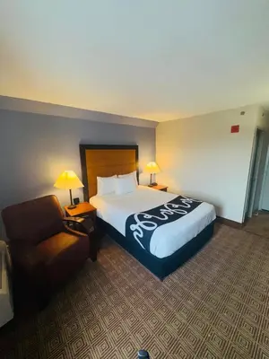 a hotel room with a large bed and a chair at La Quinta by Wyndham Stamford / New York City in Stamford