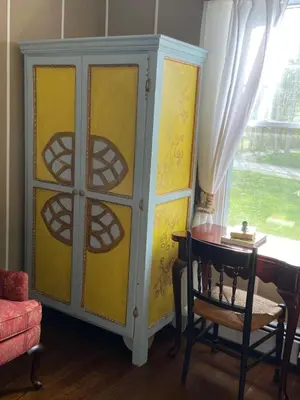a yellow cabinet with a table and a desk at Elegantly English Catskills in Liberty