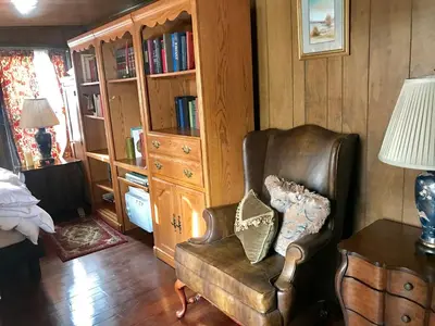 a living room with a chair and a book shelf at Elegantly English Catskills in Liberty