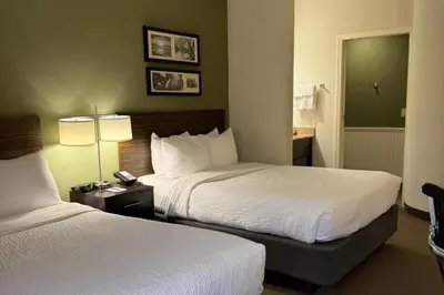 a hotel room with two beds and a phone at Sleep Inn & Suites Queensbury - Lake George in Queensbury