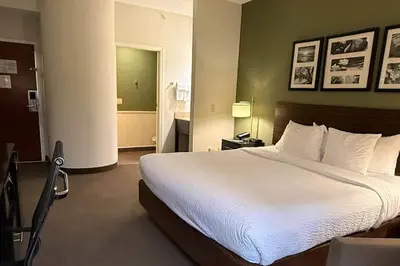 a bedroom with a large white bed and a bathroom at Sleep Inn & Suites Queensbury - Lake George in Queensbury