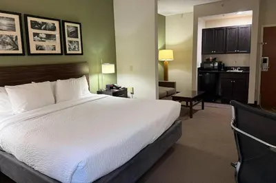 a hotel room with a bed and a kitchen at Sleep Inn & Suites Queensbury - Lake George in Queensbury