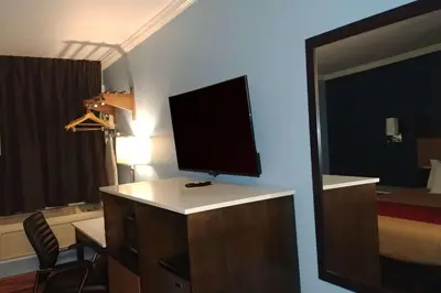 a room with a television on a dresser with a bedroom at Econo Lodge Milldale - Southington in Plantsville