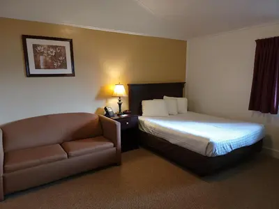 a hotel room with a bed and a couch at Hickory Grove Motor Inn - Cooperstown in Cooperstown