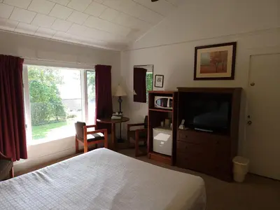 a bedroom with a bed and a television and a desk at Hickory Grove Motor Inn - Cooperstown in Cooperstown