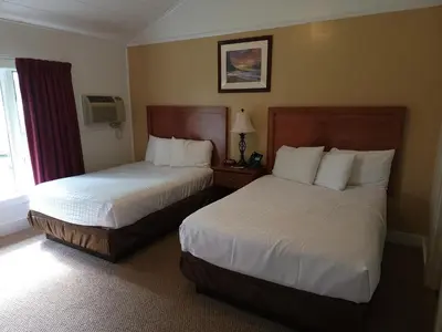 a hotel room with two beds and a window at Hickory Grove Motor Inn - Cooperstown in Cooperstown