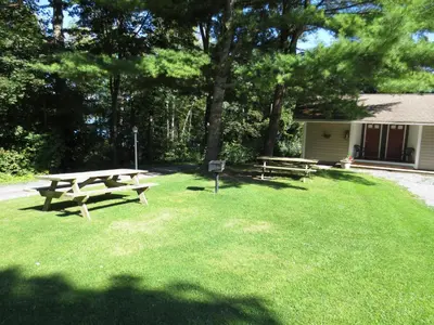 two picnic tables sitting in a field of grass at Hickory Grove Motor Inn - Cooperstown in Cooperstown